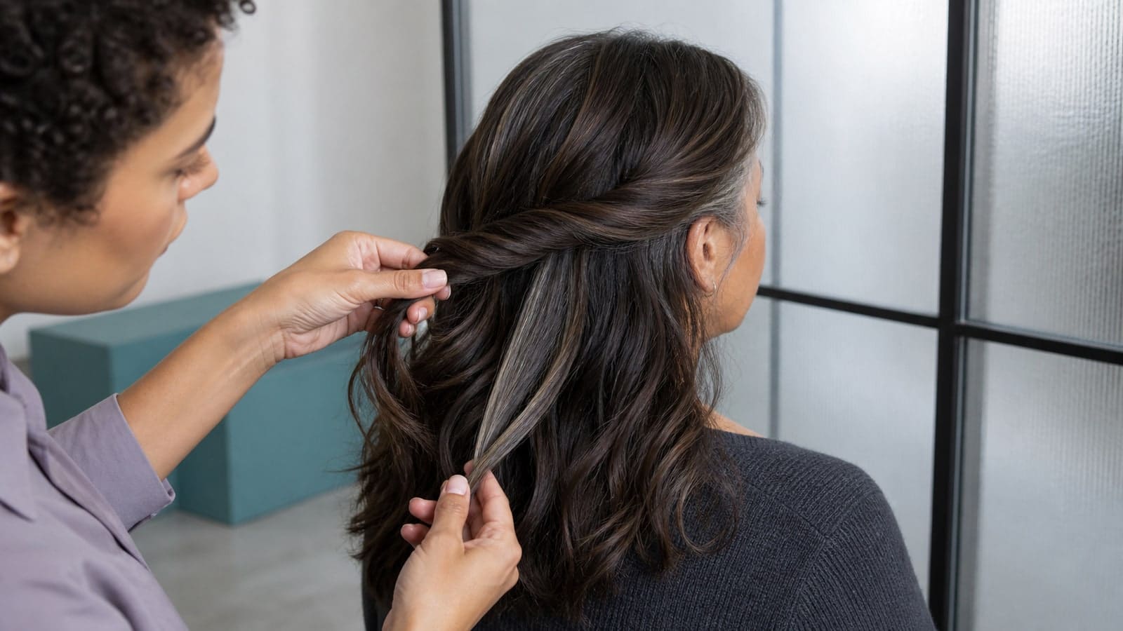 Colorist releases a narrow deep-ash ribbon and smoky lowlight from a client's cool cocoa-brown wavy hair