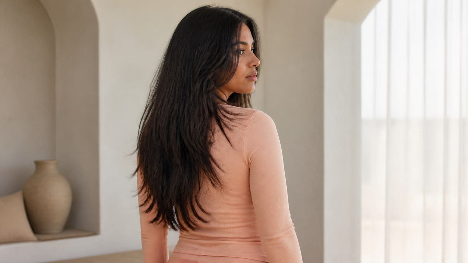 Oval-like face in a back-three-quarter view with long dark layers, cheek-level framing, and complete chest-length ends